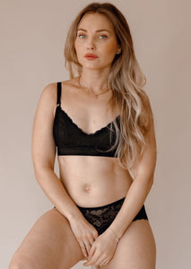 Model sitting on a chair wearing Valeria nursing bra and Leia hipster in black 